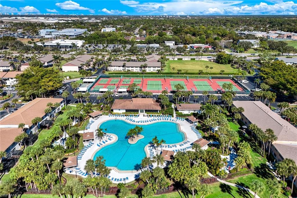 Community amenities featuring a large freeform swimming pool, multiple tennis courts, and lush landscaping
