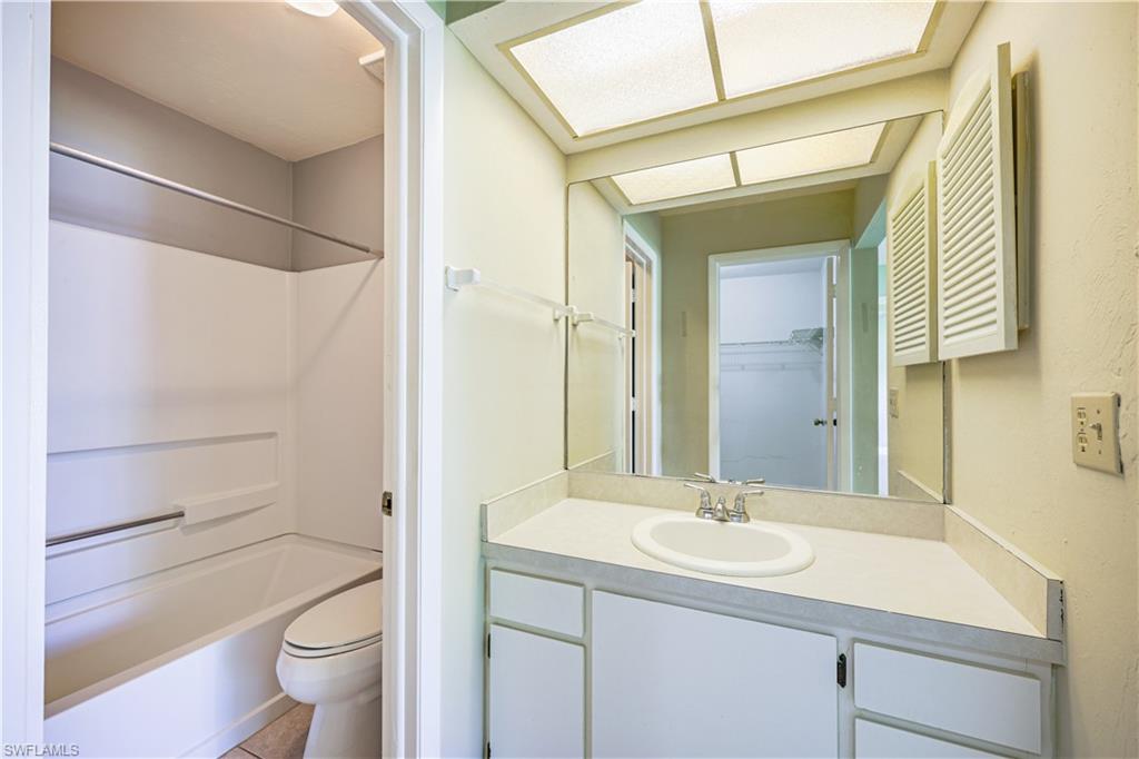 Built-in vanity with an integrated sink and base cabinetry, large wall-mounted mirror, and a combined tub and shower unit