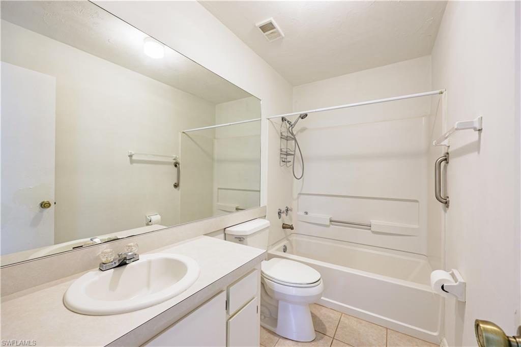 Bright, updated bathroom featuring a large frameless mirror, oval sink with chrome fixtures, and tile surround