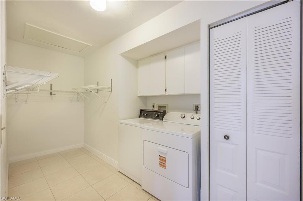 Laundry area featuring tile flooring, ceiling-mounted light fixture, built-in cabinetry, and louvered bifold doors