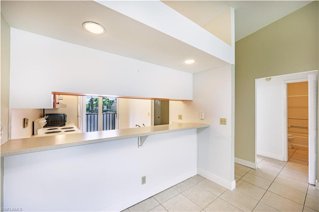 Kitchen passthrough window with a breakfast bar, recessed lighting, and tile flooring