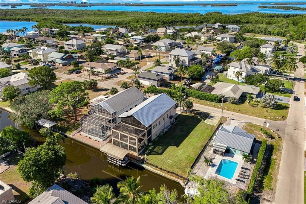 Aerial perspective of suburban area featuring a nearby body of water and a pool