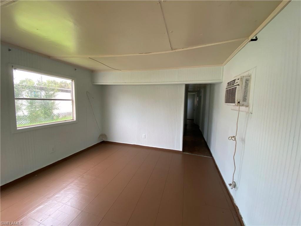 Empty room with a wall mounted AC and wood-type flooring