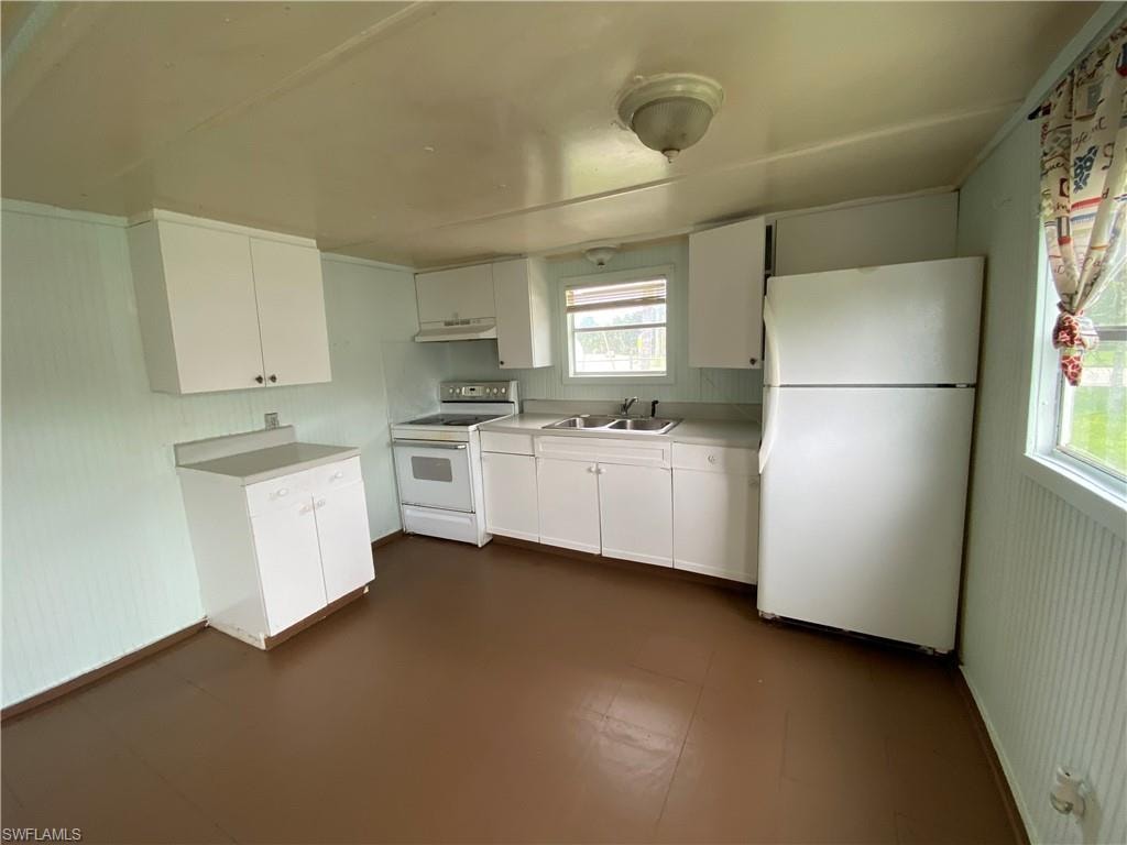 Kitchen with a wealth of natural light, white appliances, white cabinets, and sink
