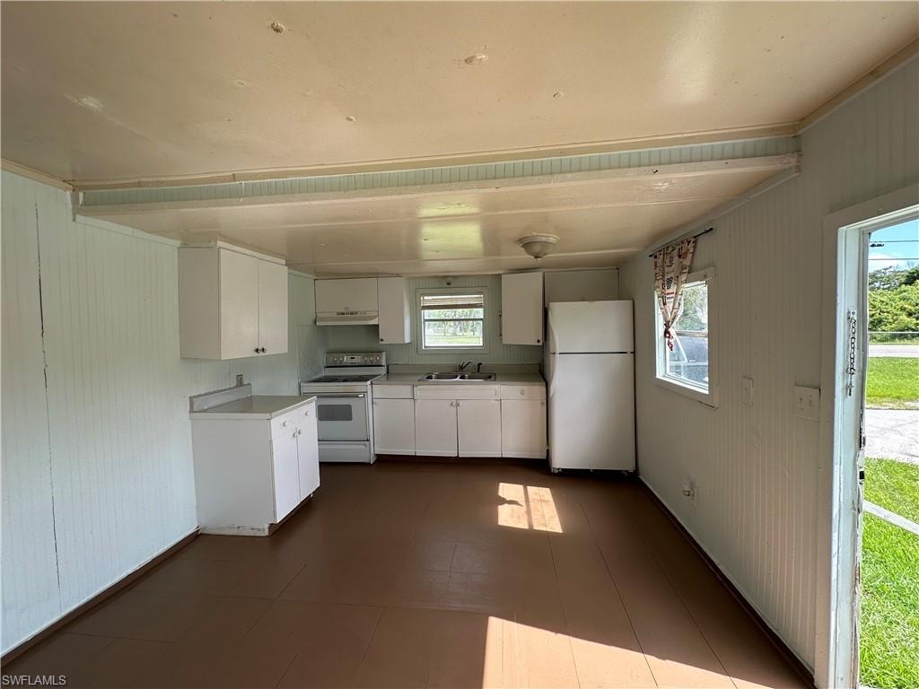 Kitchen featuring tile patterned floors, sink, white cabinetry, and white appliances
