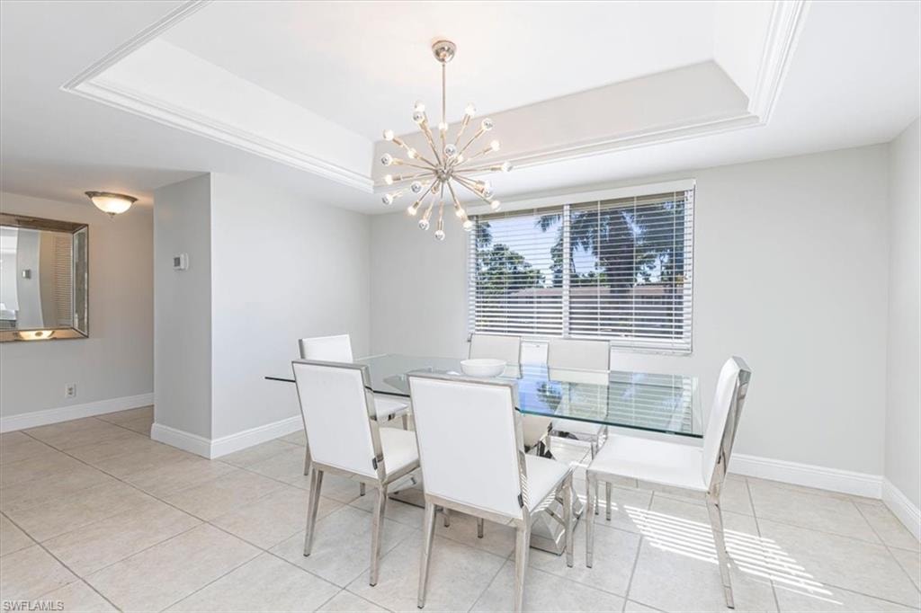 Dining area featuring a raised ceiling, a chandelier, and light tile patterned floors