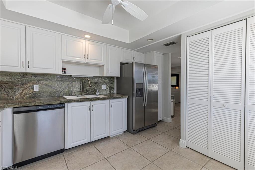 Kitchen featuring white cabinetry, appliances with stainless steel finishes, tasteful backsplash, open shelves, and light tile patterned floors