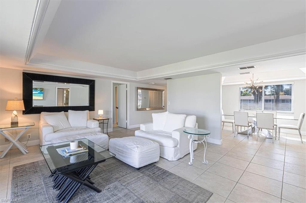 Tiled living room with baseboards and a tray ceiling
