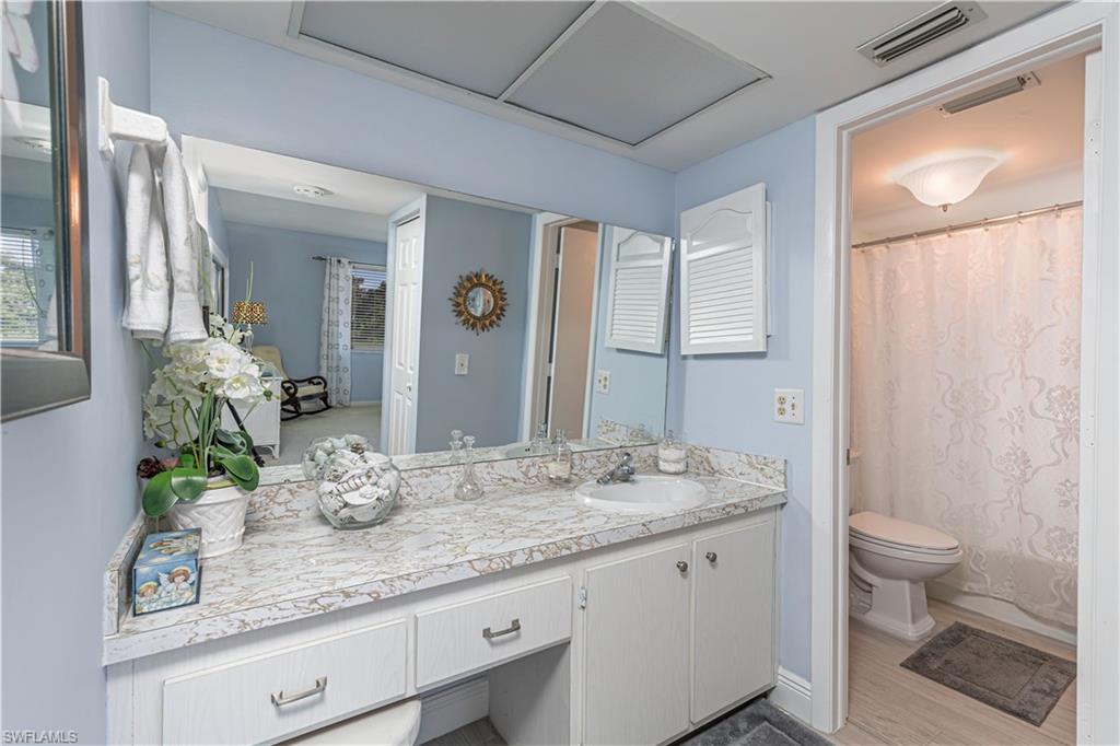 Bathroom with curtained shower, vanity, and light wood finished floors
