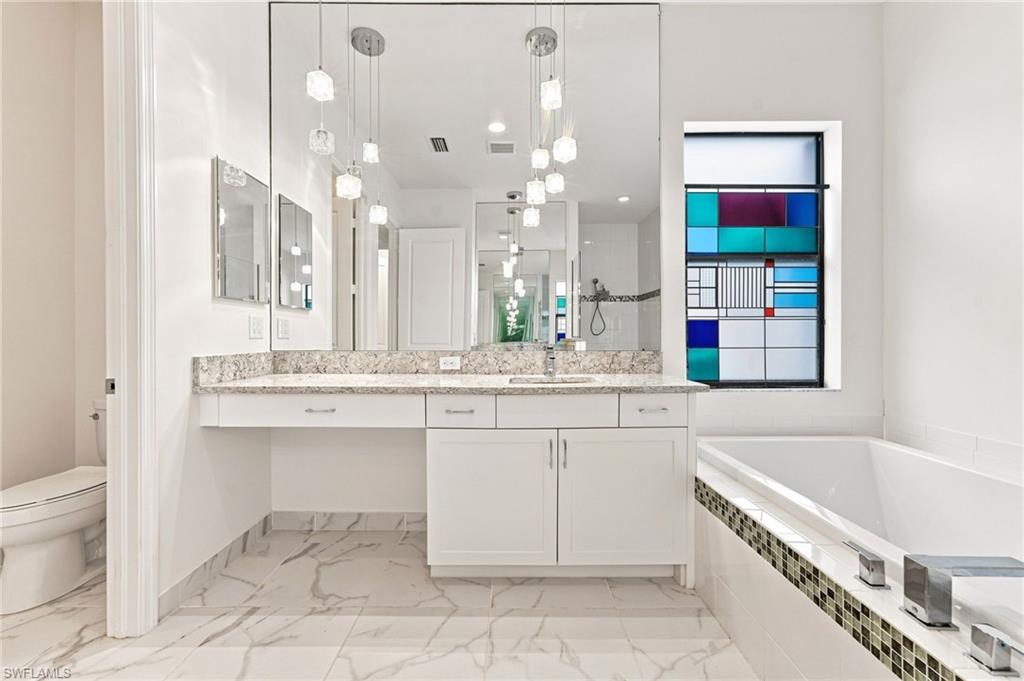Primary ensuite bathroom with Roman soaking tub, dual vanities, luxury finishes.