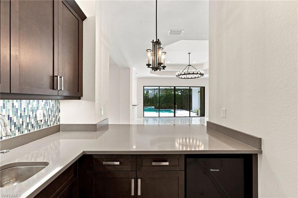Wet bar with sink, counter seating and beverage fridge