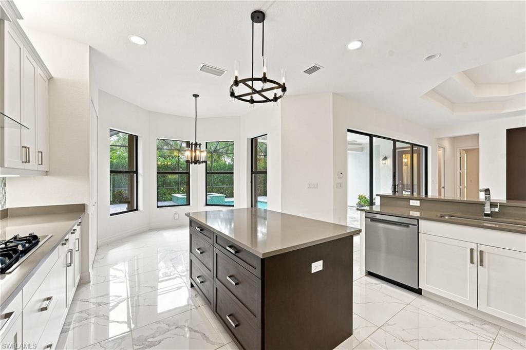 Open gourmet kitchen with stainless steel appliances and vented hood to outside, casual dining area, large center island.
