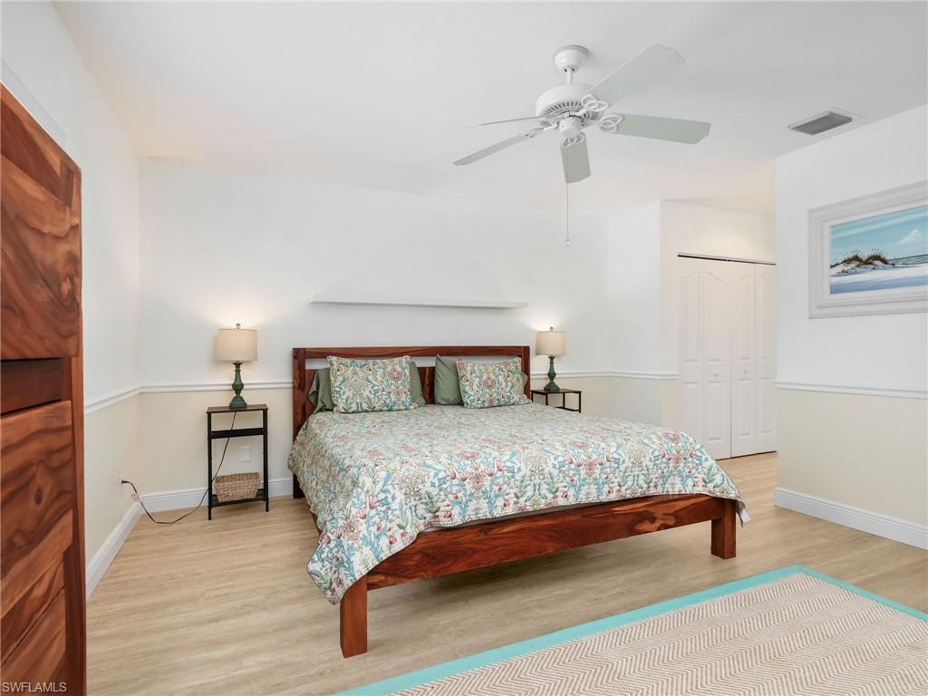 Wood-finish flooring, bi-fold closet doors, crown molding, and a ceiling fan with integrated lighting