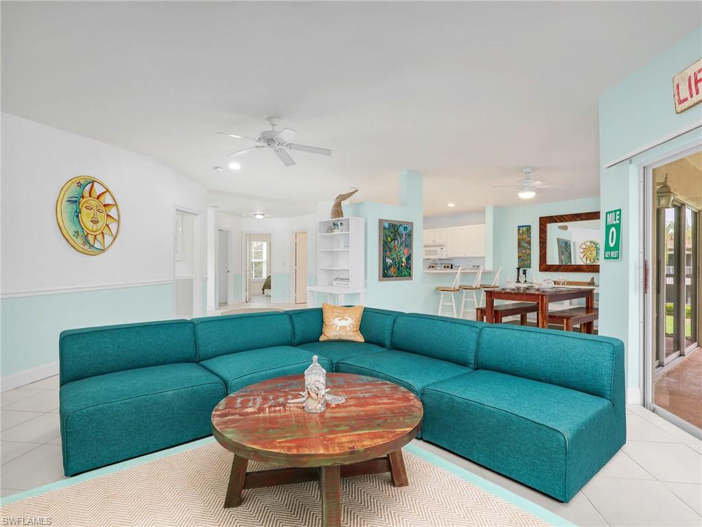 Open-concept living area featuring light tile flooring, white walls with a light blue wainscoting, and recessed lighting