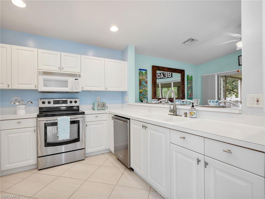 Kitchen featuring white cabinetry, stainless steel appliances, solid surface countertops, and tile flooring