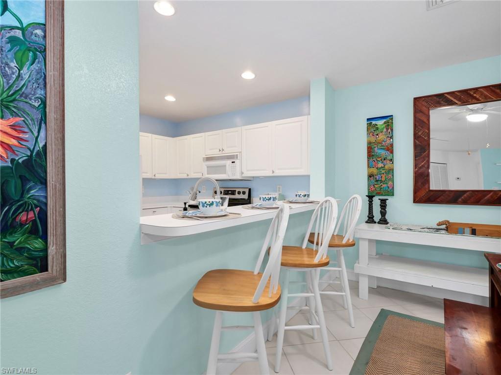 Kitchen pass-through with white cabinetry, recessed lighting, and white countertops