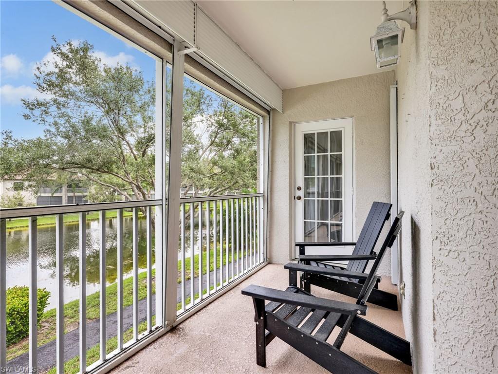 Screened balcony with textured stucco finish, white railing, and a multi-pane door
