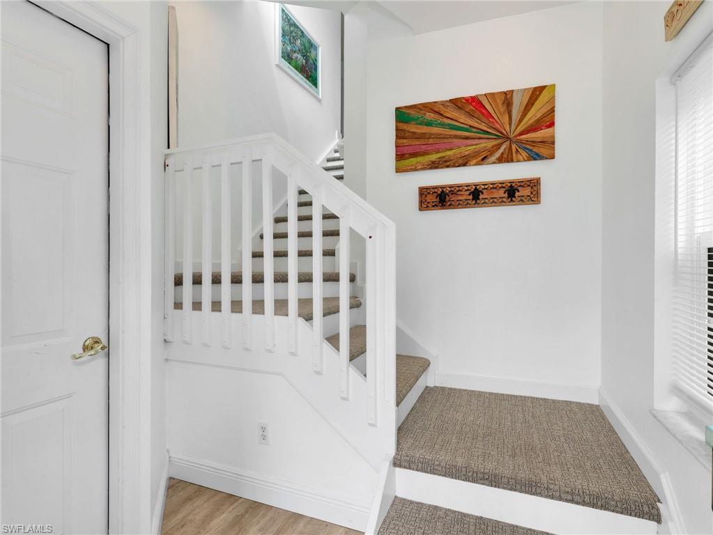 White painted staircase with carpeted treads, white balusters, and a white handrail