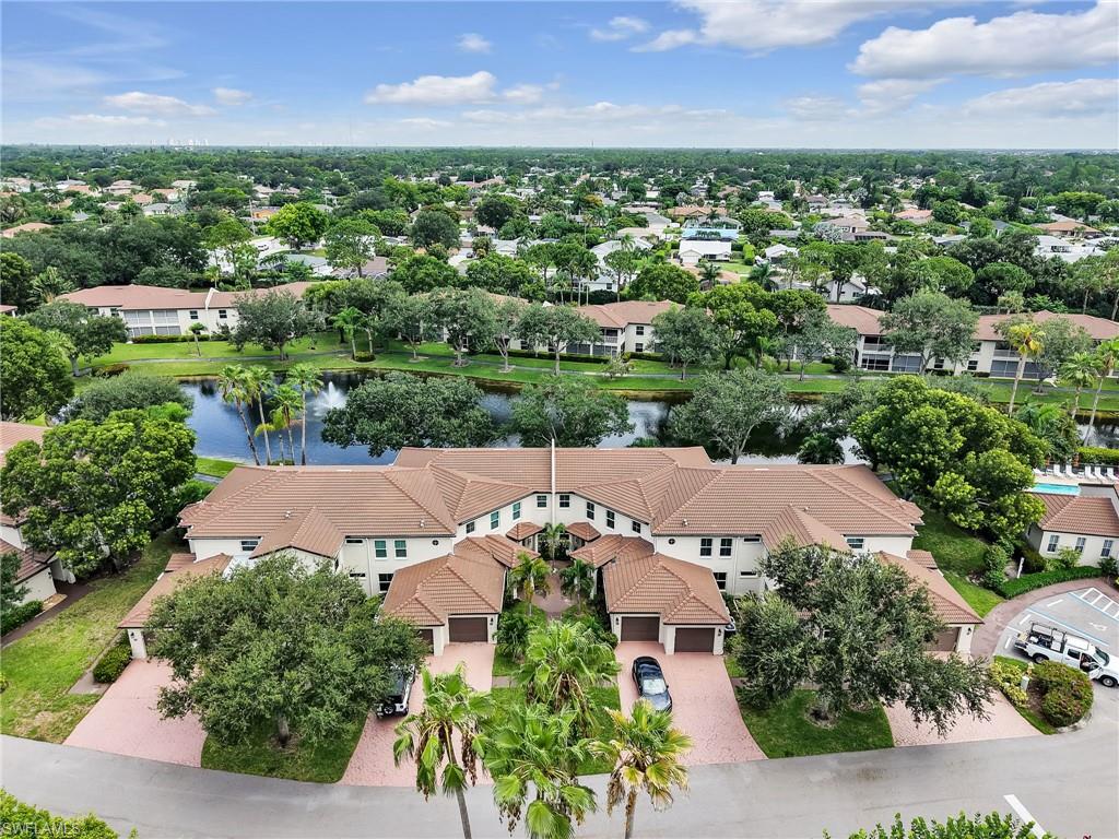 Stucco exterior with tile roofing, paver driveways, attached garages, mature landscaping, and a water feature