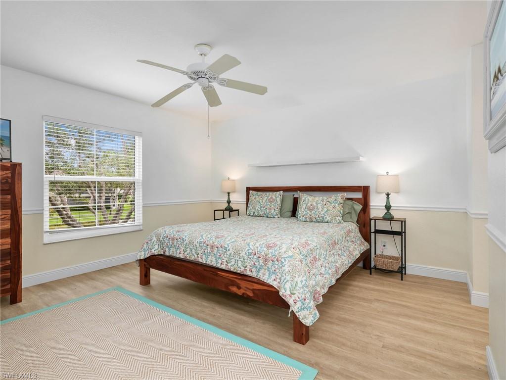Hard-surface flooring, crown molding, picture rail detail, ceiling fan, and large window