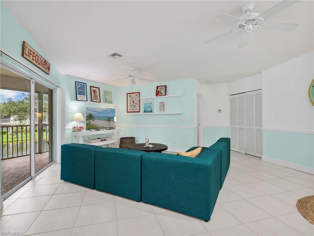 Spacious living area featuring diagonal tile flooring, sliding glass doors, built-in shelving, and two ceiling fans