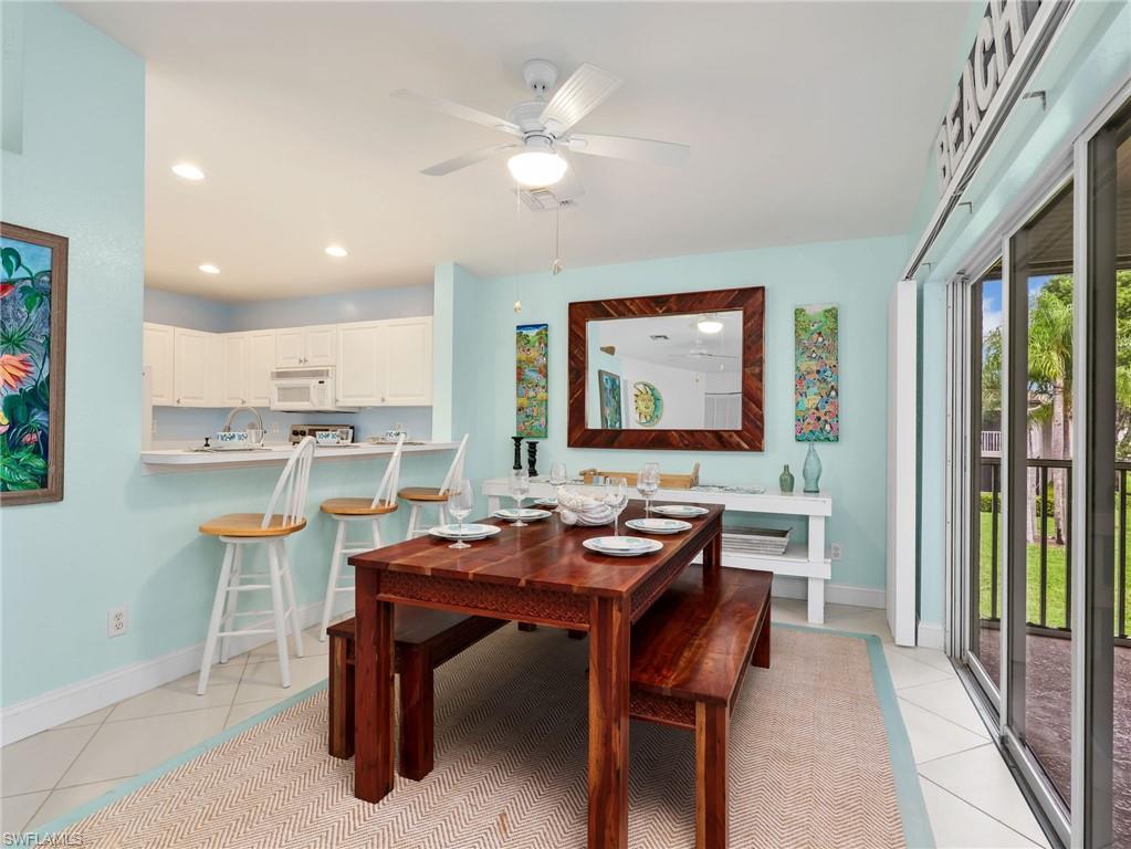Recessed lighting, wood-finish dining set, ceiling fan, white kitchen cabinetry, and sliding glass doors