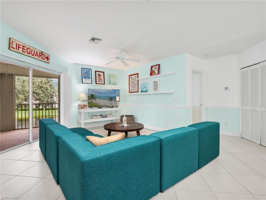 Sliding glass door opening to a private balcony, ceiling fan, tile flooring, and louvered bifold doors