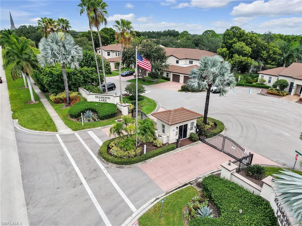 Gated entry with a security booth, paver driveway, and mature landscaping