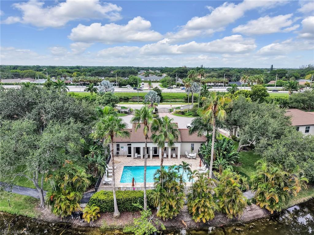 Property featuring a swimming pool, mature palm trees, lush landscaping, and a tile roof