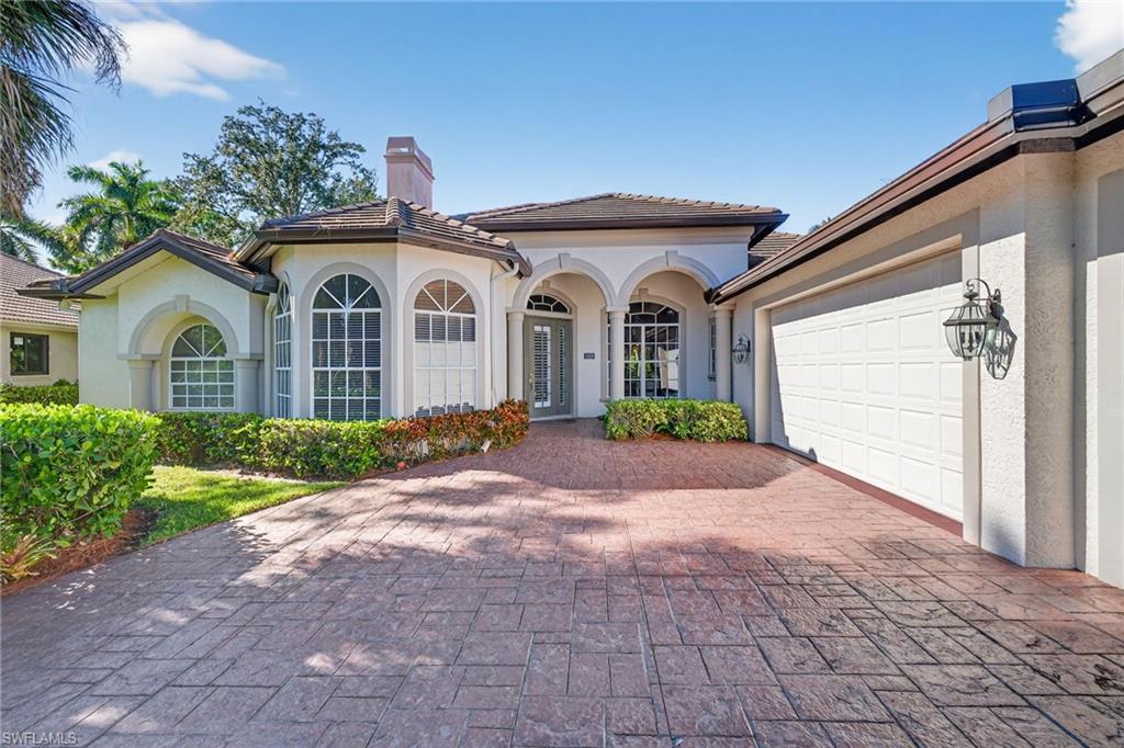 Mediterranean / spanish-style house with stucco siding, decorative driveway, a chimney, and a garage