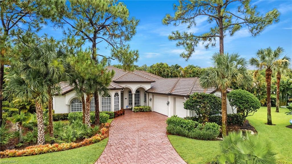 Mediterranean / spanish-style house with a garage, stucco siding, a tile roof, decorative driveway, and a front lawn