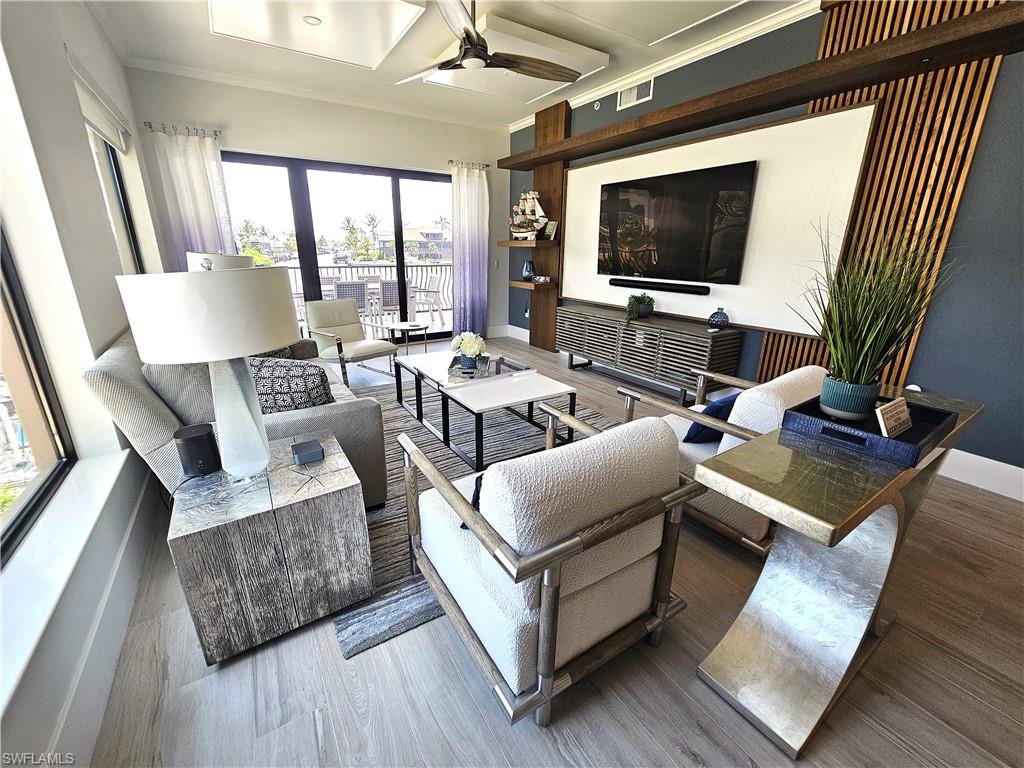Living area with crown molding, wood finished floors, and ceiling fan