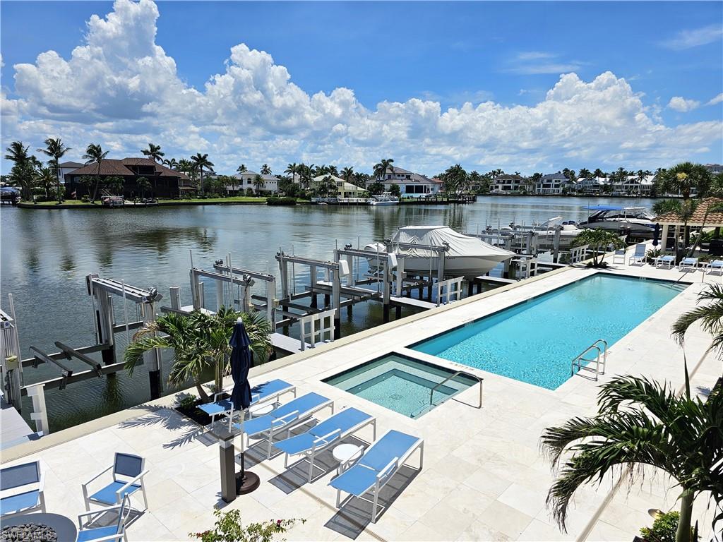 Community pool with boat lift, a community hot tub, a water view, and a boat dock
