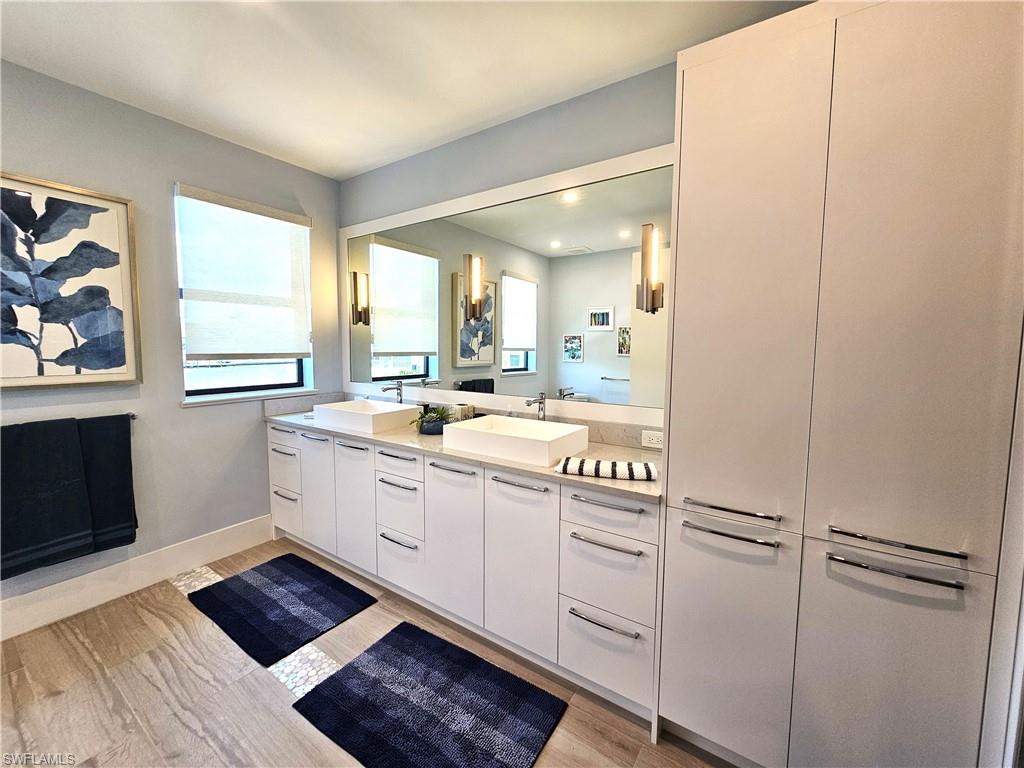 Bathroom featuring plenty of natural light, double vanity, light wood-style flooring, and recessed lighting