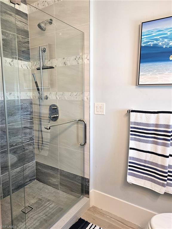 Full bathroom featuring a shower stall and baseboards