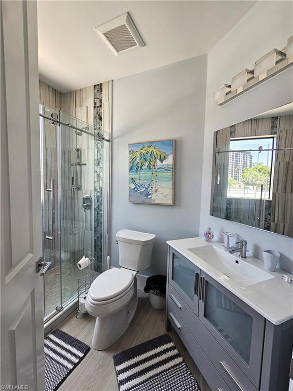 Full bath featuring vanity, light wood-style floors, and a stall shower