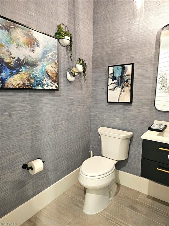 Half bath featuring vanity, wood finished floors, and wallpapered walls