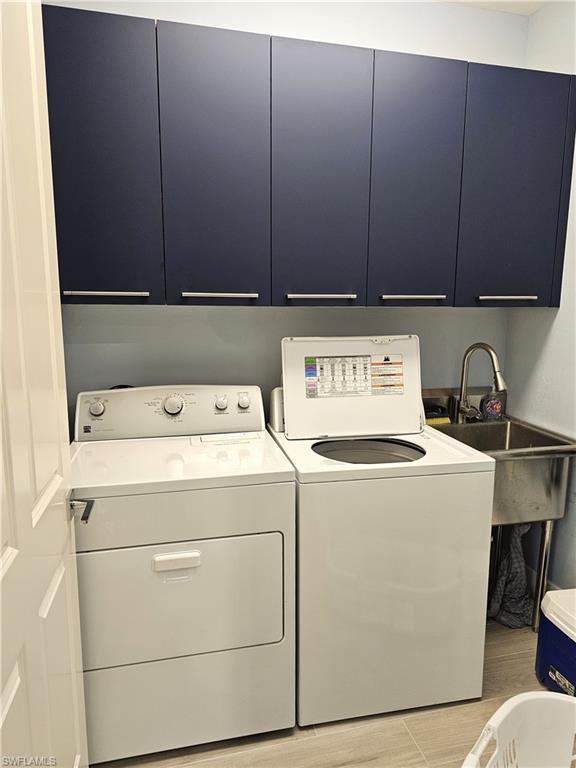 Laundry room with cabinet space, washer and clothes dryer, and light wood finished floors