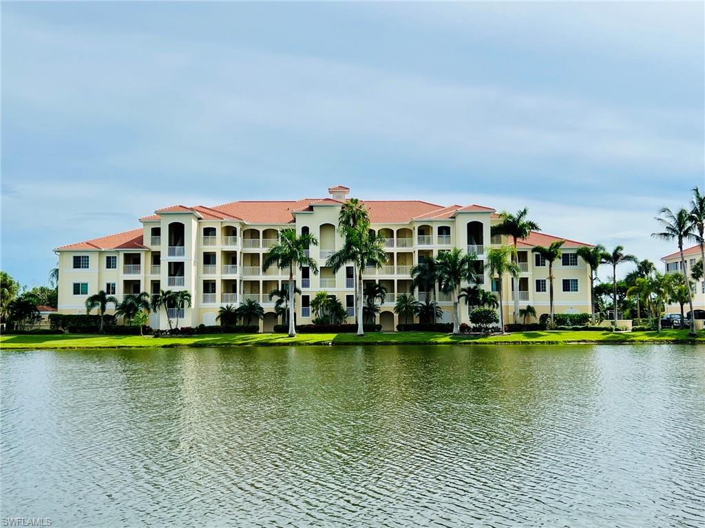 Mediterranean-inspired architecture with a barrel tile roof, multiple private balconies, lush green landscaping, and a waterfront setting
