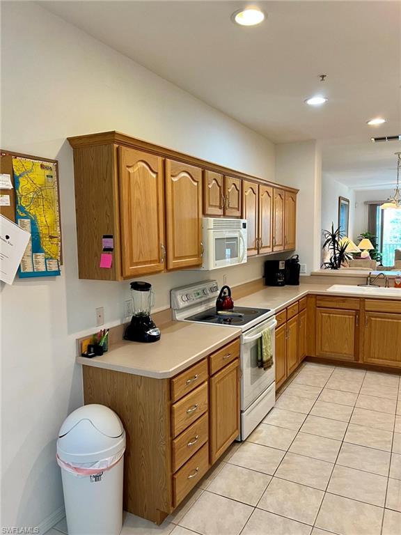 Kitchen featuring wood-finish cabinetry, neutral countertops, recessed lighting, and tile flooring