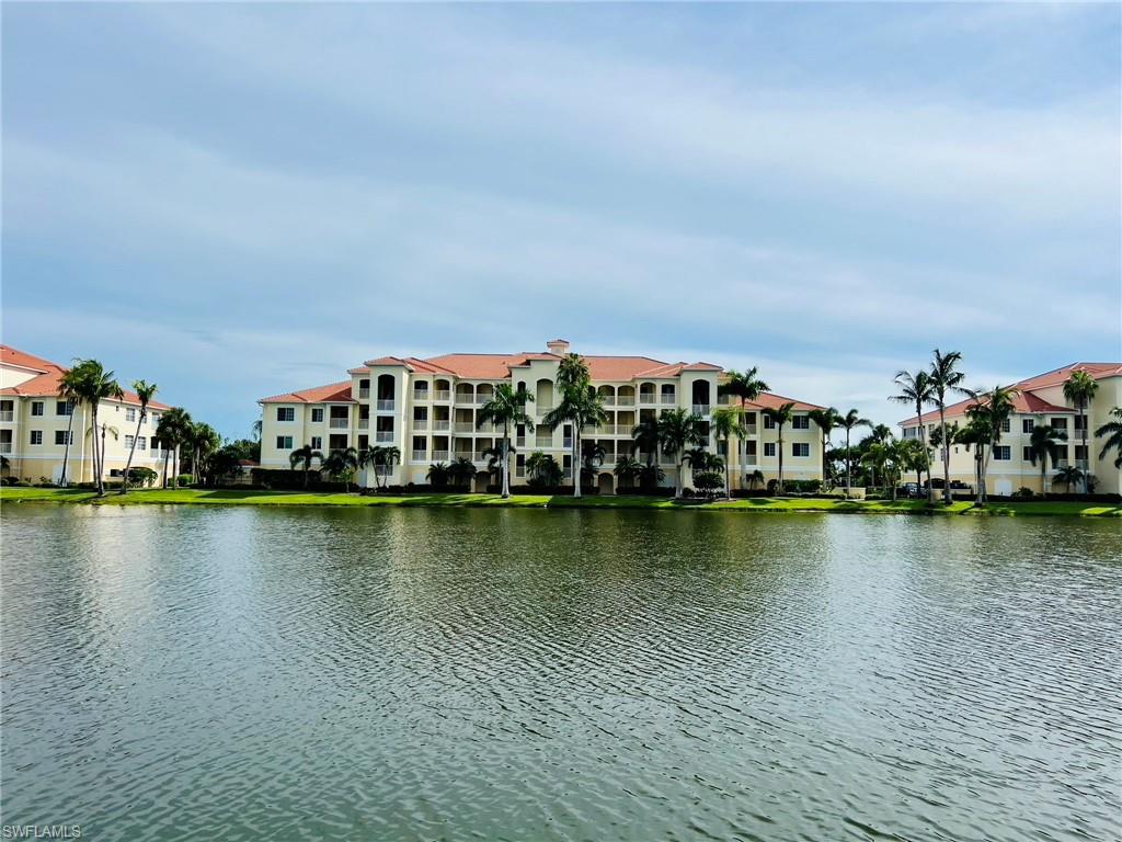 Waterfront property featuring multiple buildings with terracotta-style roofs, balconies, and surrounding mature palm trees