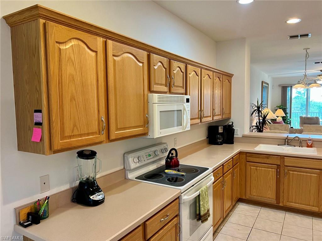 Warm wood cabinetry throughout the kitchen features arched door panels and ample storage, complemented by a neutral solid-surface countertop
