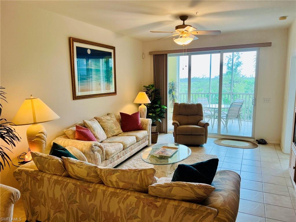 Sliding glass doors opening to a screened balcony, ceiling fan with integrated lighting, tiled flooring, and neutral wall tones