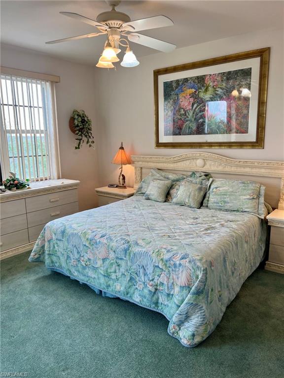 Textured carpet, ceiling fan with integrated lighting, window with horizontal blinds, built-in dresser, and decorative headboard