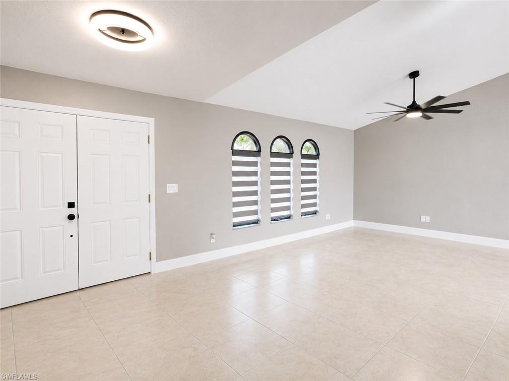 Vaulted ceiling with a contemporary ceiling fan, dual entry doors, three arched windows with blinds, recessed lighting, and tile flooring