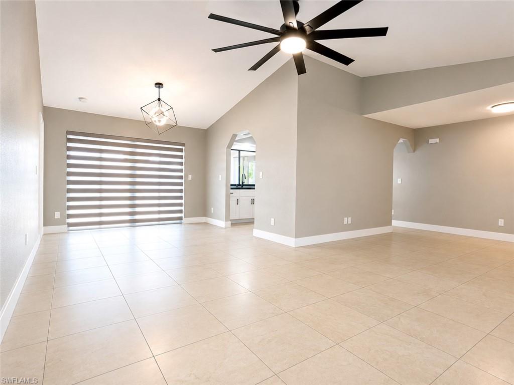 Open-concept room featuring light-toned tile flooring, vaulted ceilings, and a contemporary ceiling fan