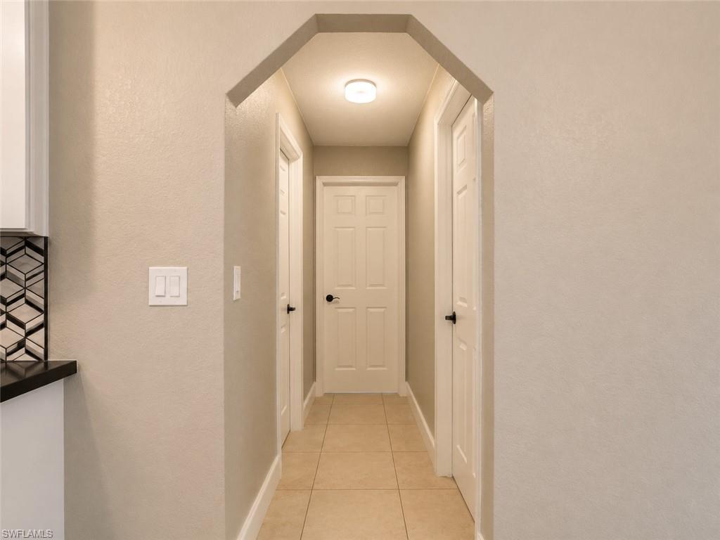 Elegant hallway featuring coffered ceiling details, tile flooring, and multiple closet doors with brushed nickel hardware