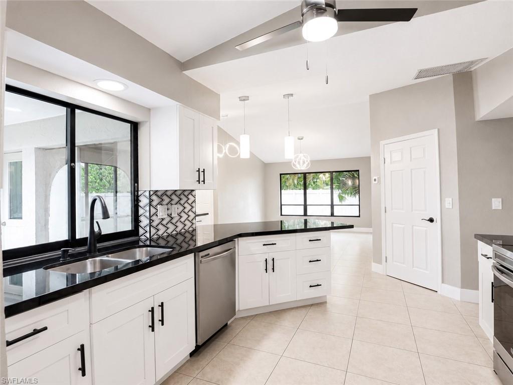 Kitchen featuring white cabinetry, black countertops, stainless steel appliances, and a mosaic tile backsplash