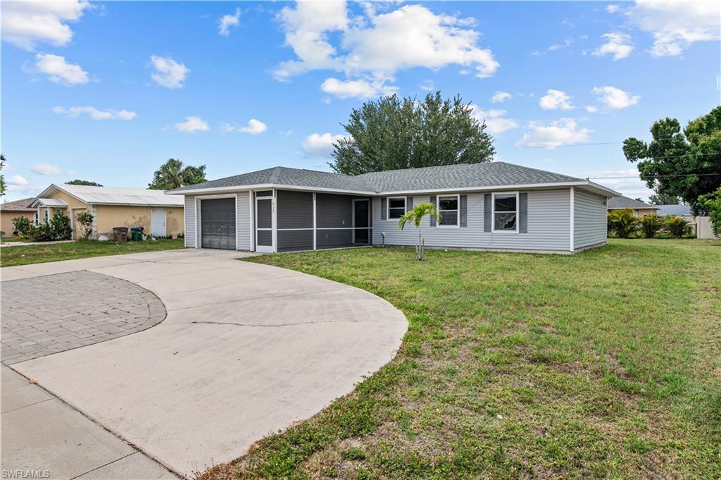 Ranch-style home with a front yard, large circle driveway and a garage