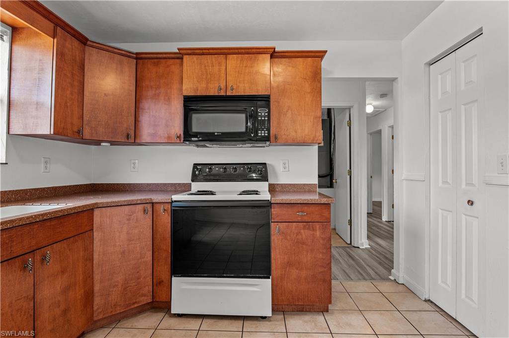 Kitchen with sink, white range with electric stovetop, and light tile floors
